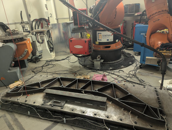 Photo. En premier plan on voit la pièce qui commence à être imprimée. En second plan, on voit la machine qui réalisse l'impression.